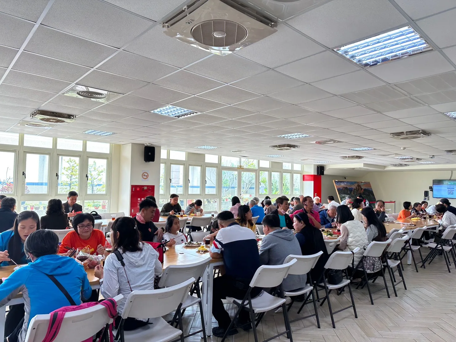 餐廳長桌並排,參加者分坐兩側用餐,遠景廣角