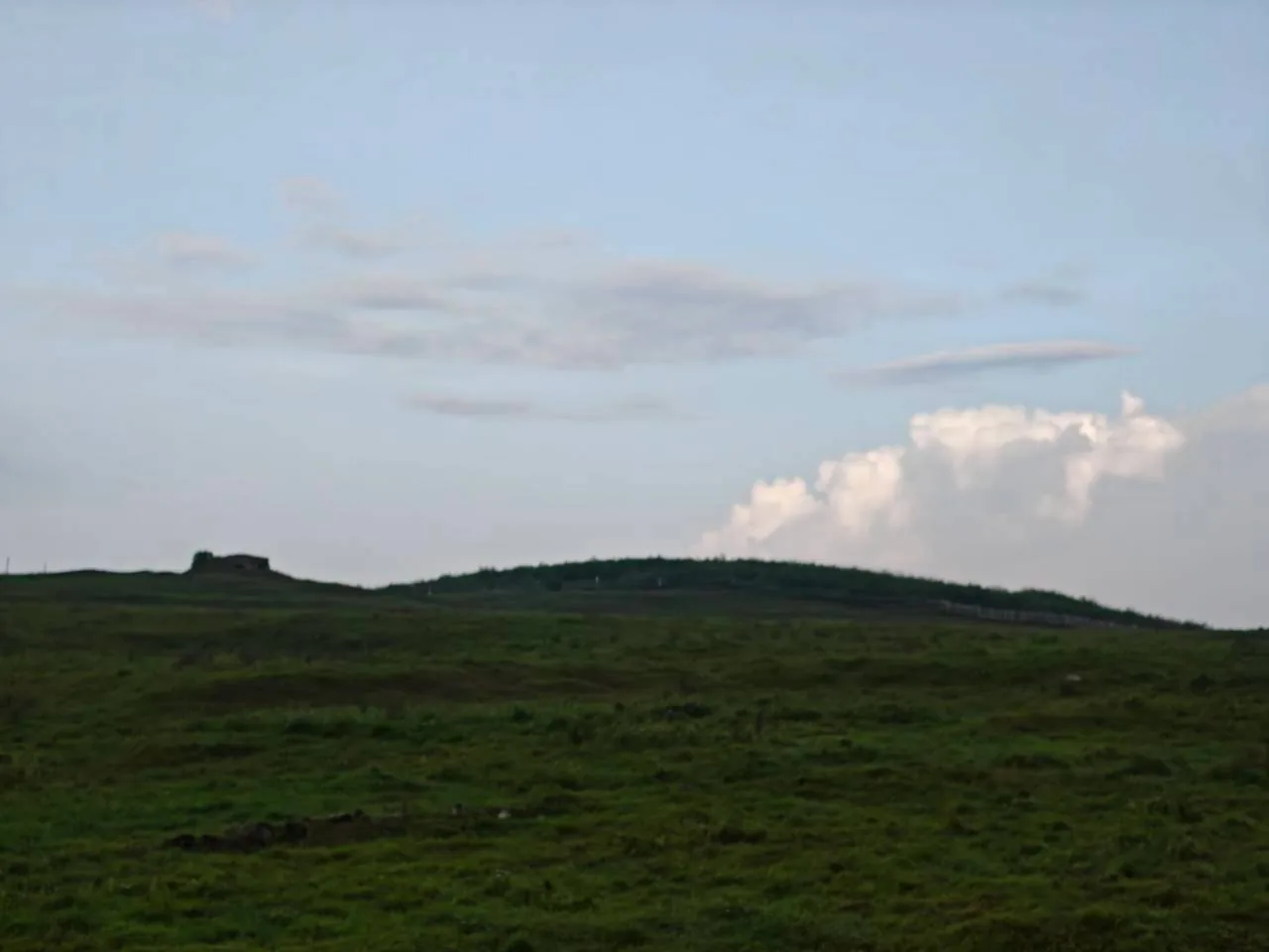 望安島的草原地景，遠方丘陵稜線上有一座石造建物